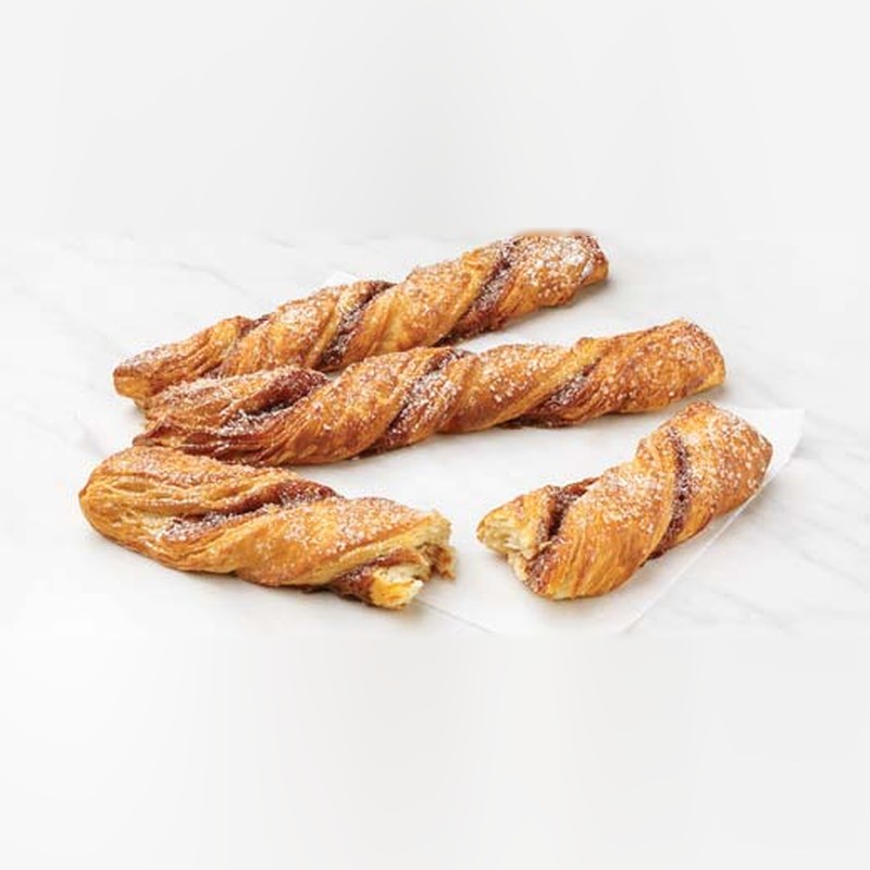 Four baked cinnamon croissant twists on parchment paper