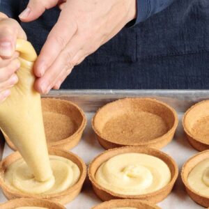 Frangipane filling piped from a piping bag into tart shells